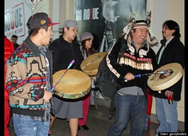 Ian Campbell (on right) a Squamish chief, leading the singing as part of INM flash mob in Vancouver, 2012; Campbell also sang and danced for the 2010 Winter Olympics which was resisted by grassroots Natives.