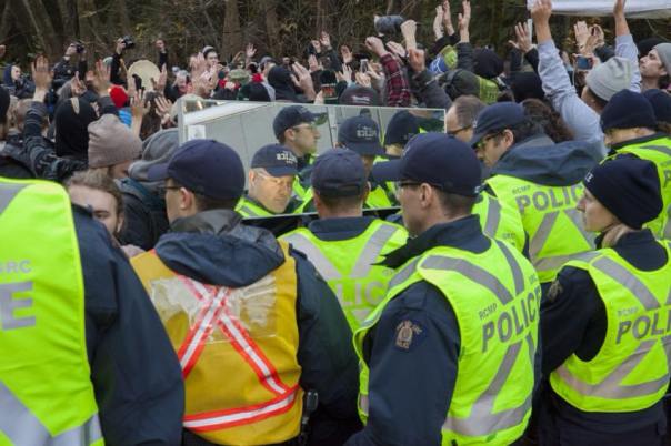 Awkward moment for cops on Burnaby Mountain as protester holds mirror in front of them, Nov 23, 2014.