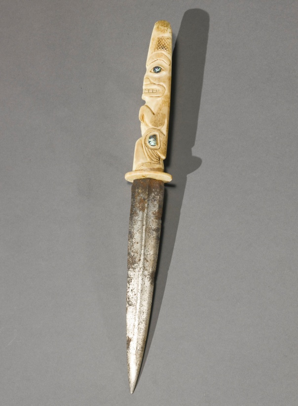 Northwest Coast Dagger, probably Tlingit the faceted blade set into an ivory handle, carved in the form of a seated bear, with pointed oval eye rims decorated with circular plaques of abalone, surmounted by another totemic animal. 13 in. length. http://www.sothebys.com auctions.